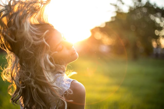 woman flipping hair with sunshine in the background